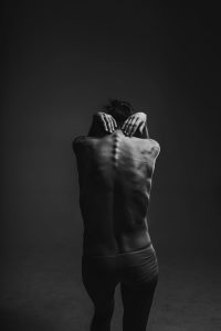 Black and white photo of woman's bare back symbolising pain